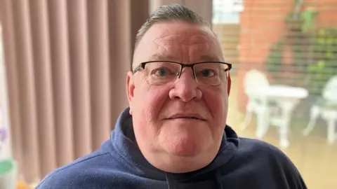 BBC Man in glasses wearing a navy blue hoodie