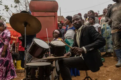 Glody Murhabazi / AFP A man plays a drum during an impromptu service in the streets of Kamituga, in South Kivu in the east of the Democratic Republic of Congo on September 20, 2024. 