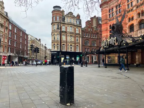 Cambridge Circus menunjukkan tonggak hitam di latar depan dengan tanda di atas Teater Palace untuk Harry Potter dan anak terkutuk di sisi kanan