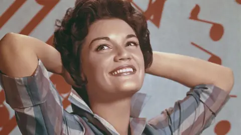Connie Francis, pictured in the 1960s, smiles while posing with her hands behind her head