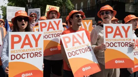 Junior doctors take part in a rally outside Downing Street, holding placards saying "pay restoration for doctors" during a strike in the run up to the general election in London.