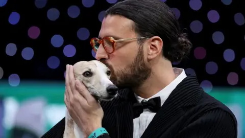 Reuters Dog handler Giovanni Liguori kisses his whippet and holds his hand to her ear