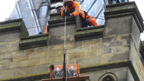 Paul Redmond Two workers pulling up the nesting box on Bradford clock tower