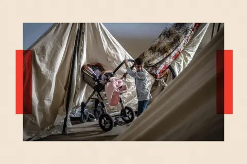 Getty Images A displaced boy pushes a stroller into his family's tent at a temporary displacement camp inside the Beirut Stadium
