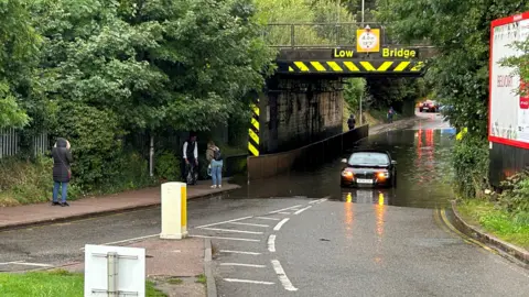 PA Media A stranded car in flood water on Cambridge Road, Hitchin