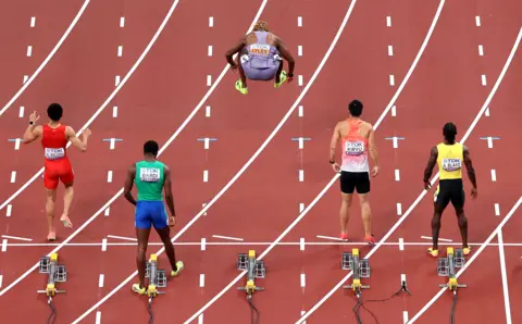 Noah Lyles jumps in the air on the start line for the 100m heats at the World Athletics Championships in Tokyo