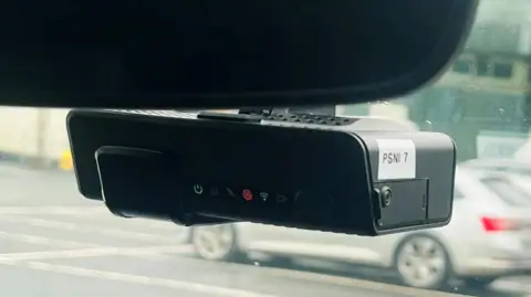 PSNI A black dash-cam installed in a PSNI vehicle. The image is taken from inside the car.
