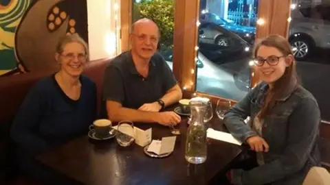 Family handout Three people sat around a dinner table in a restaurant.
