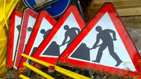 Getty Images Five 'men working' signs stacked on top of each other.