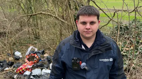 Environmental Crime Investigator Ashley Collick stands next to flytipped material used in the production of cannabis