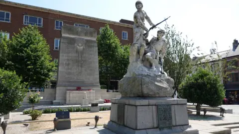 The two memorials in Paragon Square, The Boer War one has a white stone sculpture of two soldiers while the cenotaph at the back of the square is a large stone obelisk with poppies laid beside it.