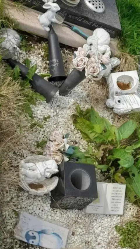 Lauren Jones An image of a grave stone with ornaments dislodged and damaged.