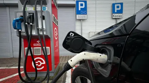 Getty afbeeldingen Een foto van een elektrische auto die op een openbaar station wordt opgeladen.