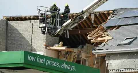 PA Two firefighters are seen near the blast site in October 2022