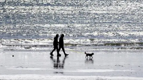 BBC A couple with a dog on a beach