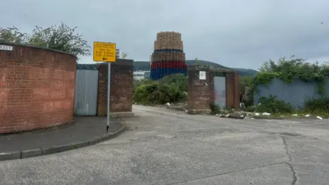 BBC The bonfire that's built with red, white and blue pallets. The entrance of the building has wood and debris on the street.