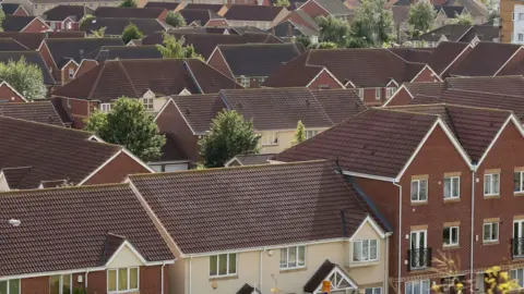 PA Media A view across the rooftops of a new-build housing estate, with properties of various sizes packed together.