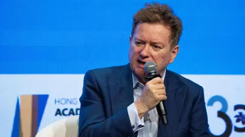 Getty Images Paul Marshall vestindo um terno azul, sentado e segurando um microfone no Hong Kong Global Financial Leaders Investment Summit em outubro de 2023