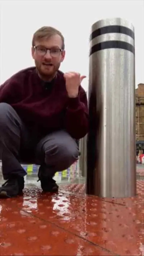 BBC reporter by bollard