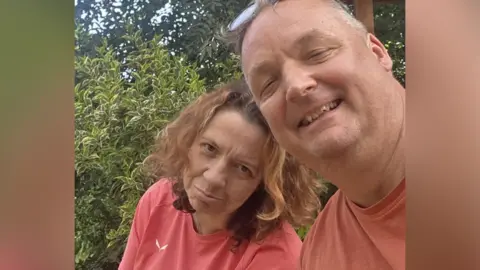 Tony Collier Collier and his wife Tracey Collier take a selfie during the fire. Tracey, with shoulder-length brown hair looks at the camera with a blank expression, while Tony smiles and is wearing a peachy coloured t-shirt.