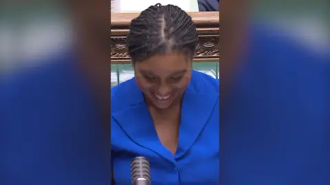 Kemi Badenoch in blue and smiling.