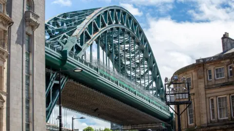 Restored section of the Tyne Bridge showing scaffolding and the structure's heavily riveted lower west arch, freshly painted in the shade Hollybush Green.