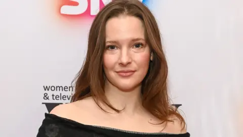 Getty Images Headshot of Morfydd. She has brunette hair and wears an off-shoulder black dress