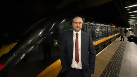 Grand Central's operations director, Chris Brandon, stands on the platform front of a Grand Central branded train. 