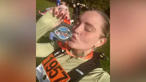 Regan Sparks A woman with blonde hair kisses a medal she has been given after running the Chelmsford half marathon