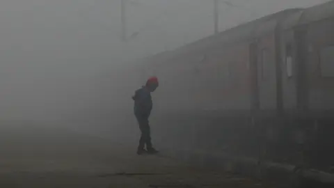 NurPhoto via Getty Images A child on a railway platform through dense smog as the temperature drops in Lucknow, India, on 23 January, 2024.