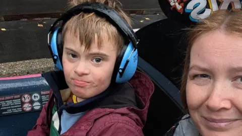 Colin Jones Coby and his mum. Coby wears light-blue-coloured ear defenders.