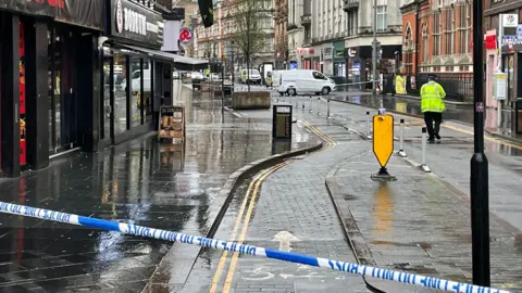 Police cordon tape across Granby Street in Leicester. A police officer stands at the scene.
