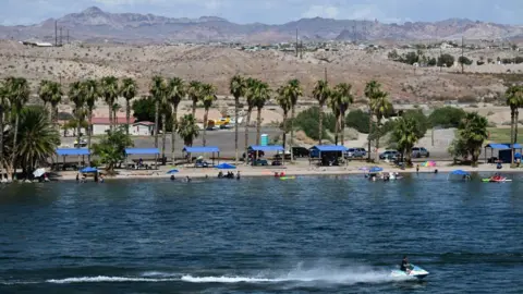 AFP via Getty Images A person rides a jet ski as others picnic in the water at Davis Camp Park on the Colorado River in Bullhead City, Arizona on June 27, 2022