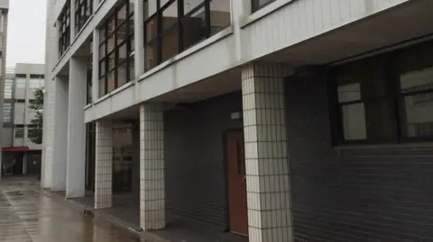 Exterior shot of the tiled, grey court building in Runcorn on a rainy day