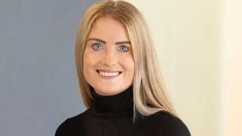 Picture of Simone White smiling at the camera in black top with blonde hair