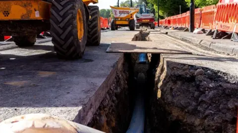An exposed water main pipe on a road
