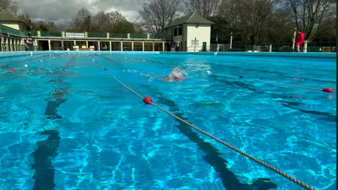 The Peterborough Lido- outdoor pool with a green building in the background 