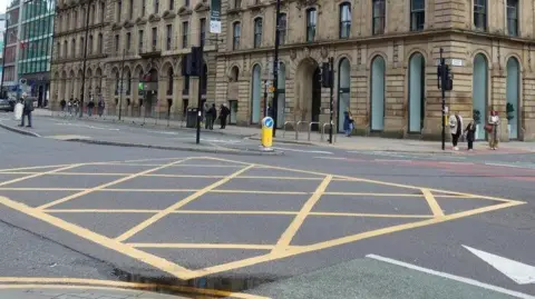 A yellow box junction is painted on a road outside a hotel in Manchester
