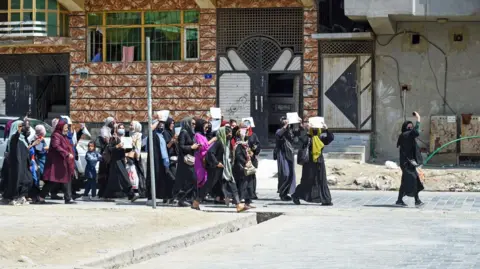 Getty Images Afghan women hold placards as they march to protest for their rights, in Kabul on April 29, 2023