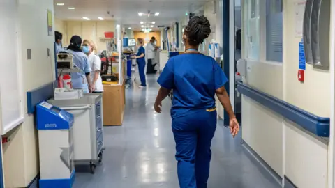 PA Media A general view of a nurse walking down a corridor on an NHS hospital ward. 