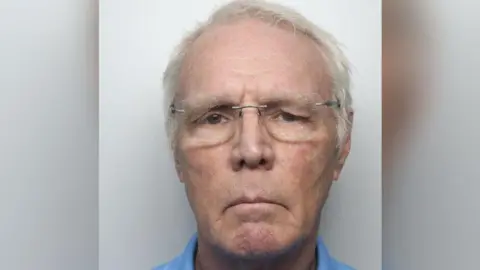 Police mugshot of Michael Haynes, who is wearing glasses and frowning at camera