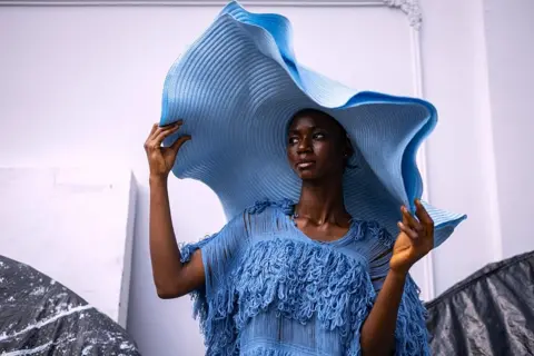 Olympia de Maismont / AFP / Getty Images A model wears a big blue hat and matching dress in Lagos - Friday 31 October 2025.