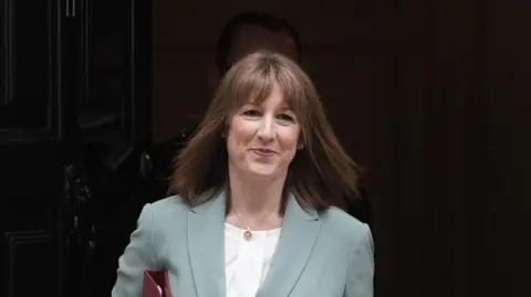 PA Media Chancellor of the Exchequer Rachel Reeves leaves 11 Downing Street, London, ahead of delivering her spending review in the House of Commons. She has shoulder length brown hair and wears a pale green suit jacket with a white blouse underneath.