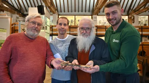 Four men cradling the fossilised bone inside a museum