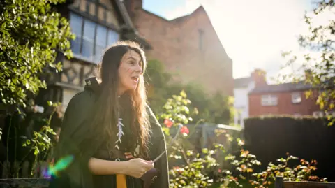 Sam Allard A woman wearing a cloak gives a performance in the grounds of Shakespeare Birthplace Trust.