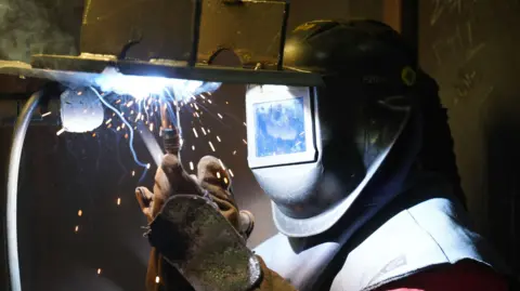 A man in a large helmet welding