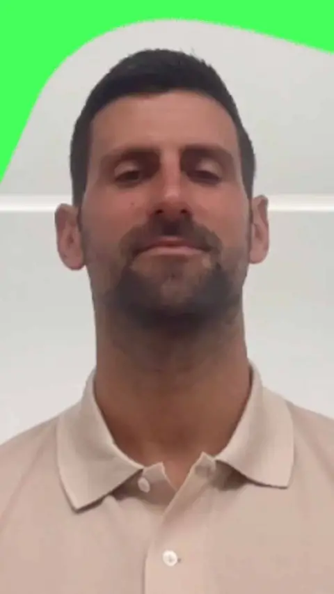 Novak Djokovic being interviewed indoors. He's wearing a cream polo shirt.