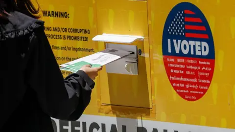A person places their Mail in ballot into a ballot box during early voting outside of the LA County Registrar-Recorder building on 1 June 2026 in Norwalk, California.