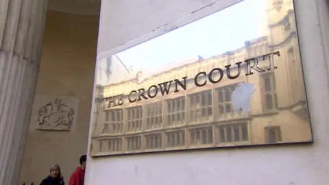 A close up shot of the brass plaque outside Bristol Crown Court that reads "Crown Court". The court's crest is visible in the background. 