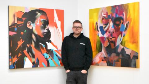 Paul Kneen in front of his artwork
